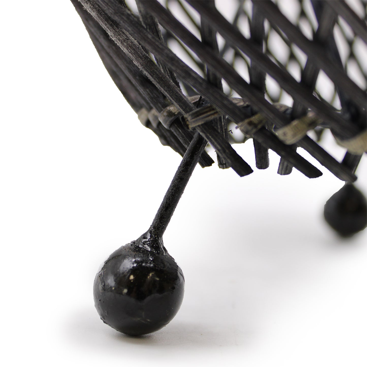 Black rattan table lamp with curved shape and metal feet, styled on white background for contemporary interiors. Foot Close Up