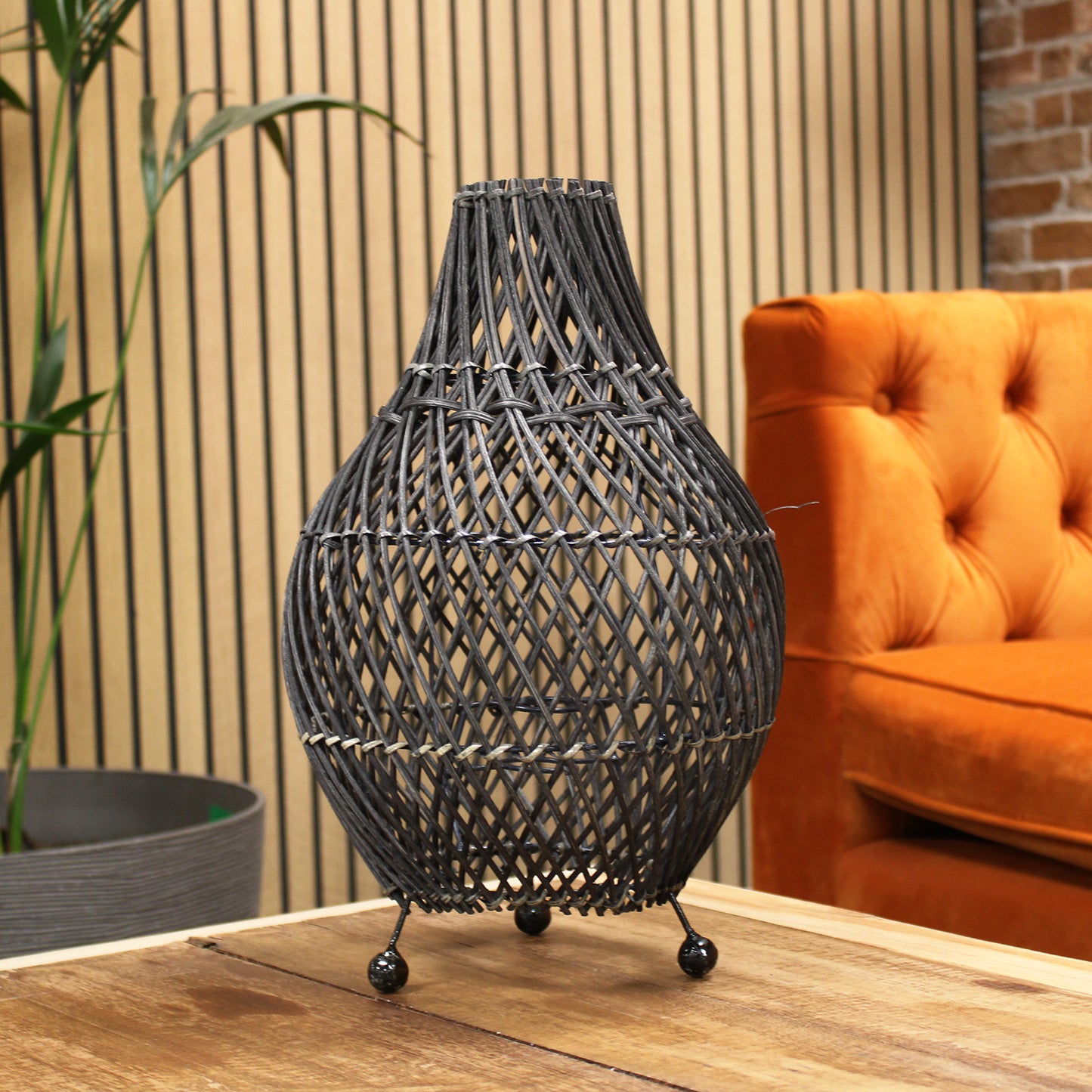 Rattan lamp glowing on wooden table next to sofa, styled for warm boho-inspired living room.