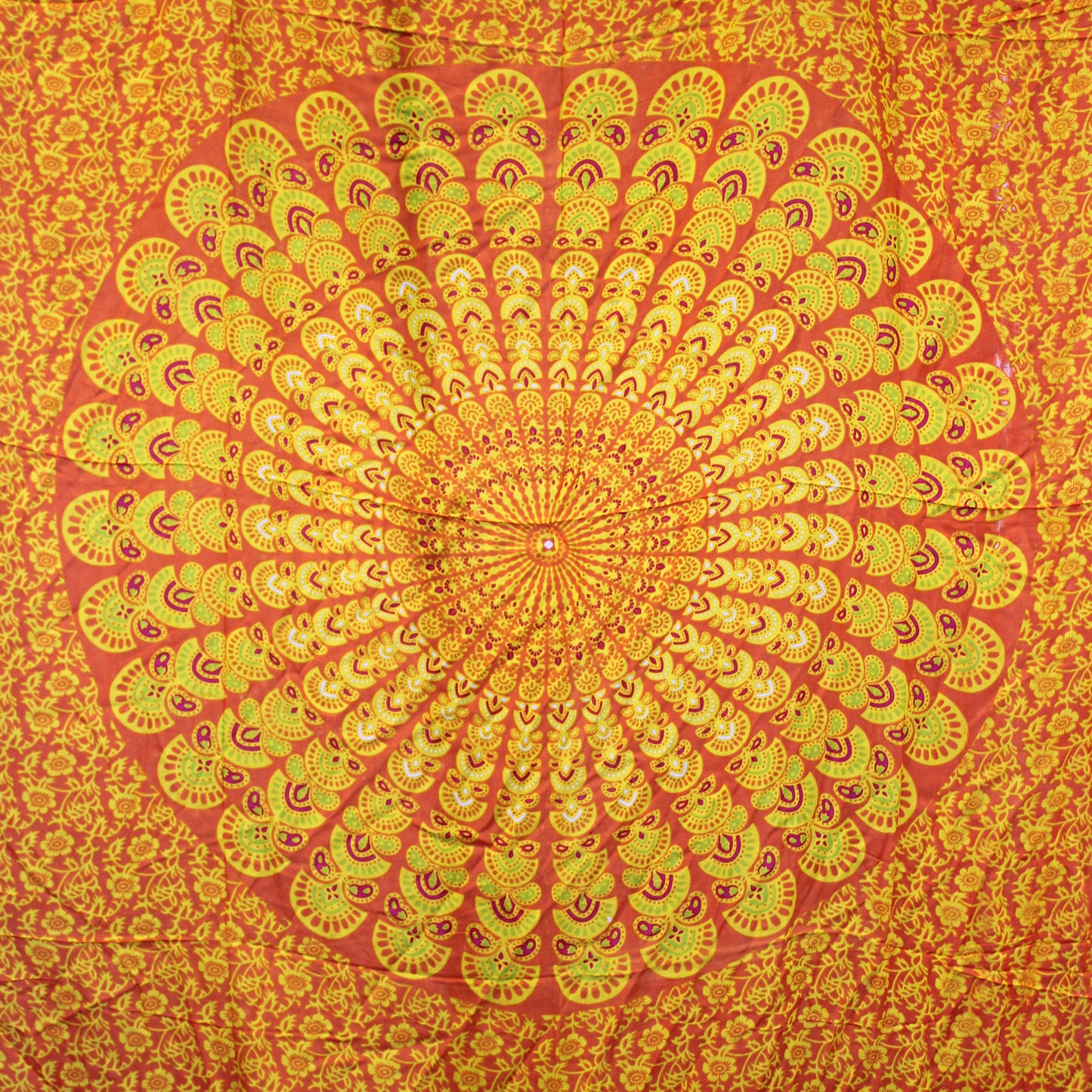 Circular mandala design in orange, yellow, and lime on full laid-out sarong with floral background
