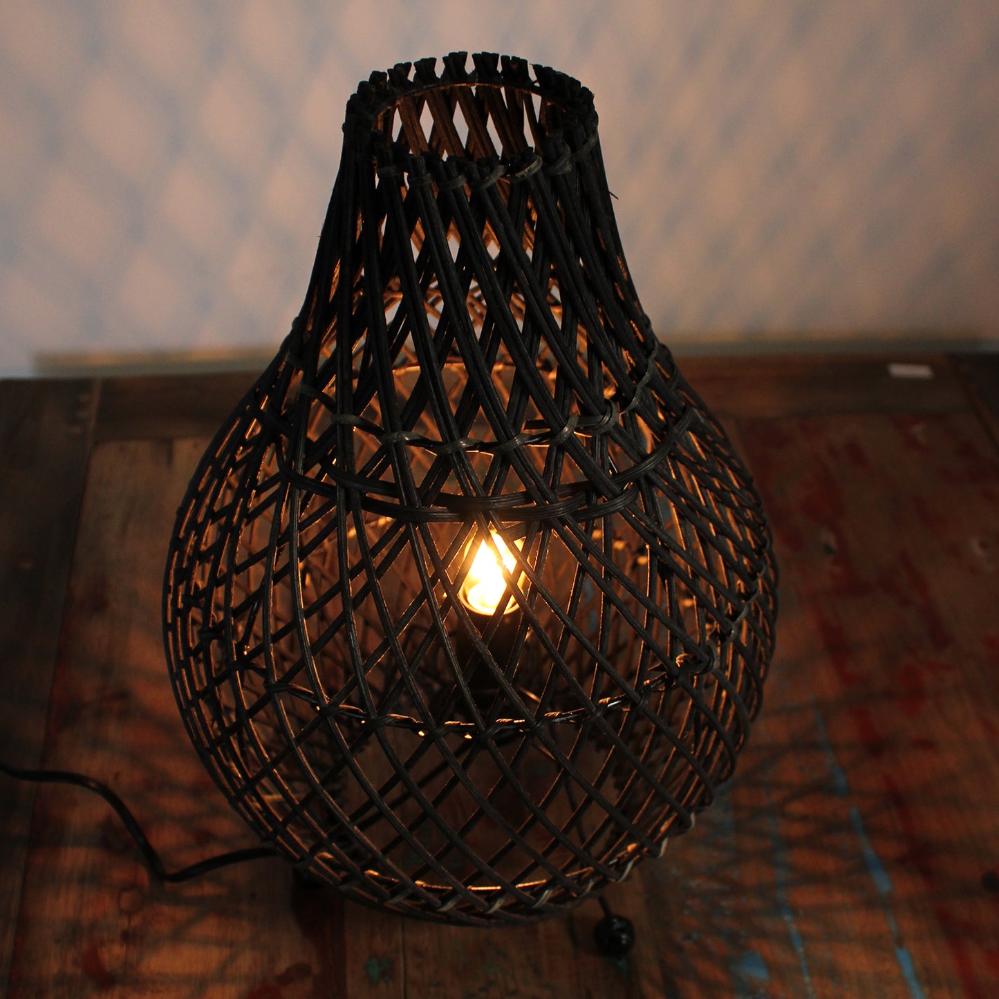 Close-up of rattan lamp glowing at night, showing detailed texture and warm ambient lighting effect.