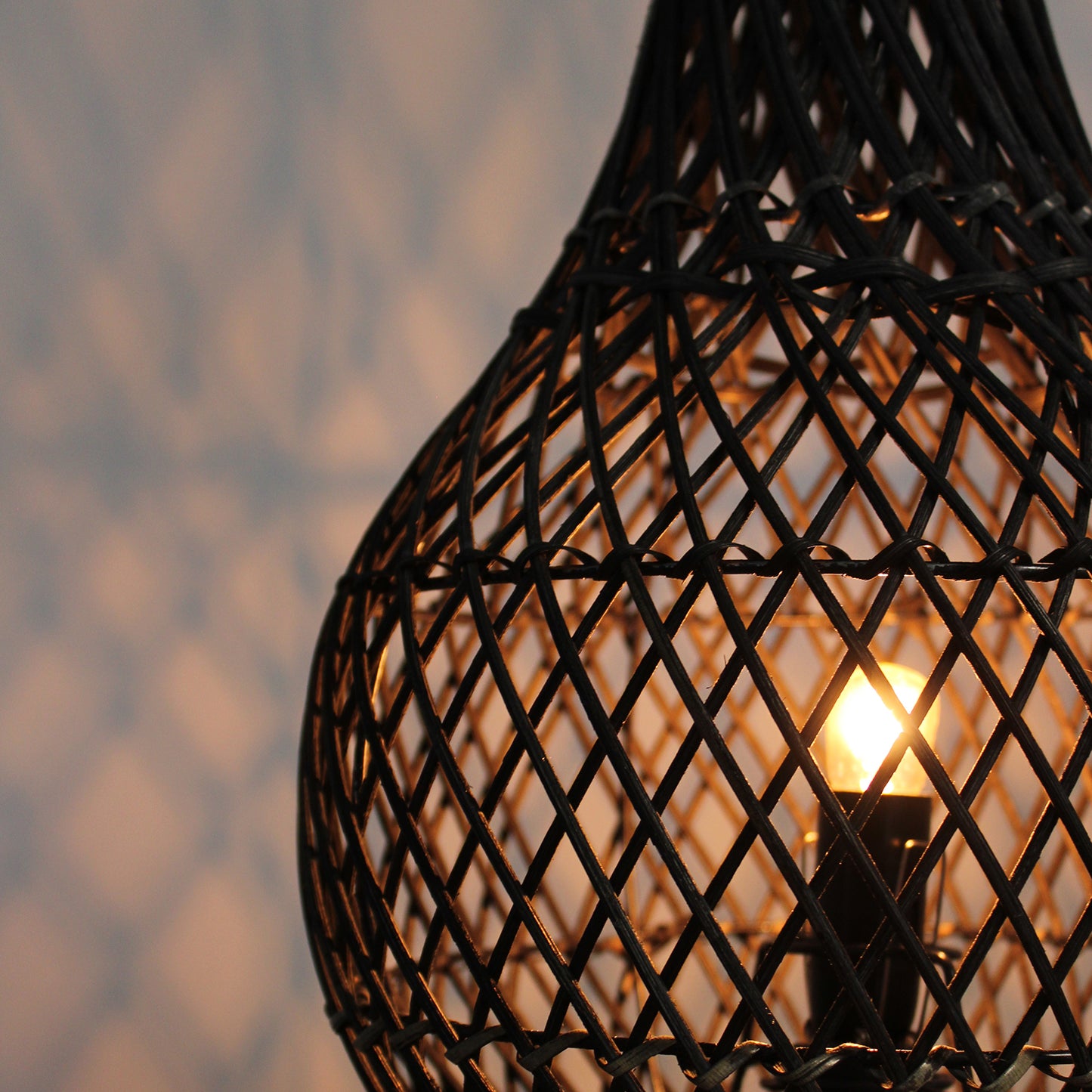 Lit rattan lamp showing side glow and light reflections on wall through woven frame.