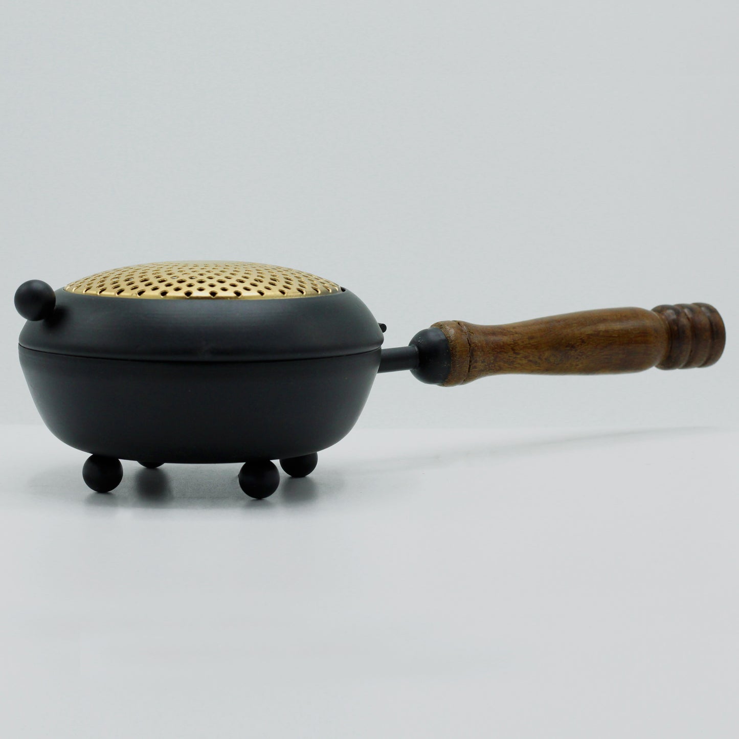 Angled view of ornate iron censer with golden accents and curved lid design, used for rituals and sacred smoke offerings.