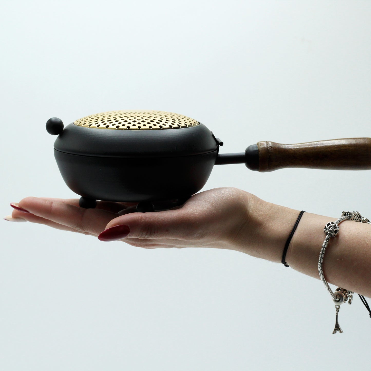 Large gold-accented iron incense burner held in hand to show scale and ceremonial utility.
