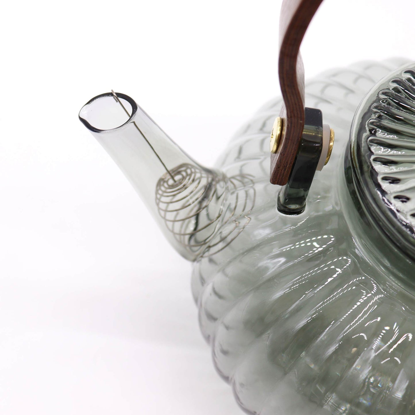 Fine detail of curved spout with charcoal-tinted glass on ribbed pearl teapot with brass-finish accents