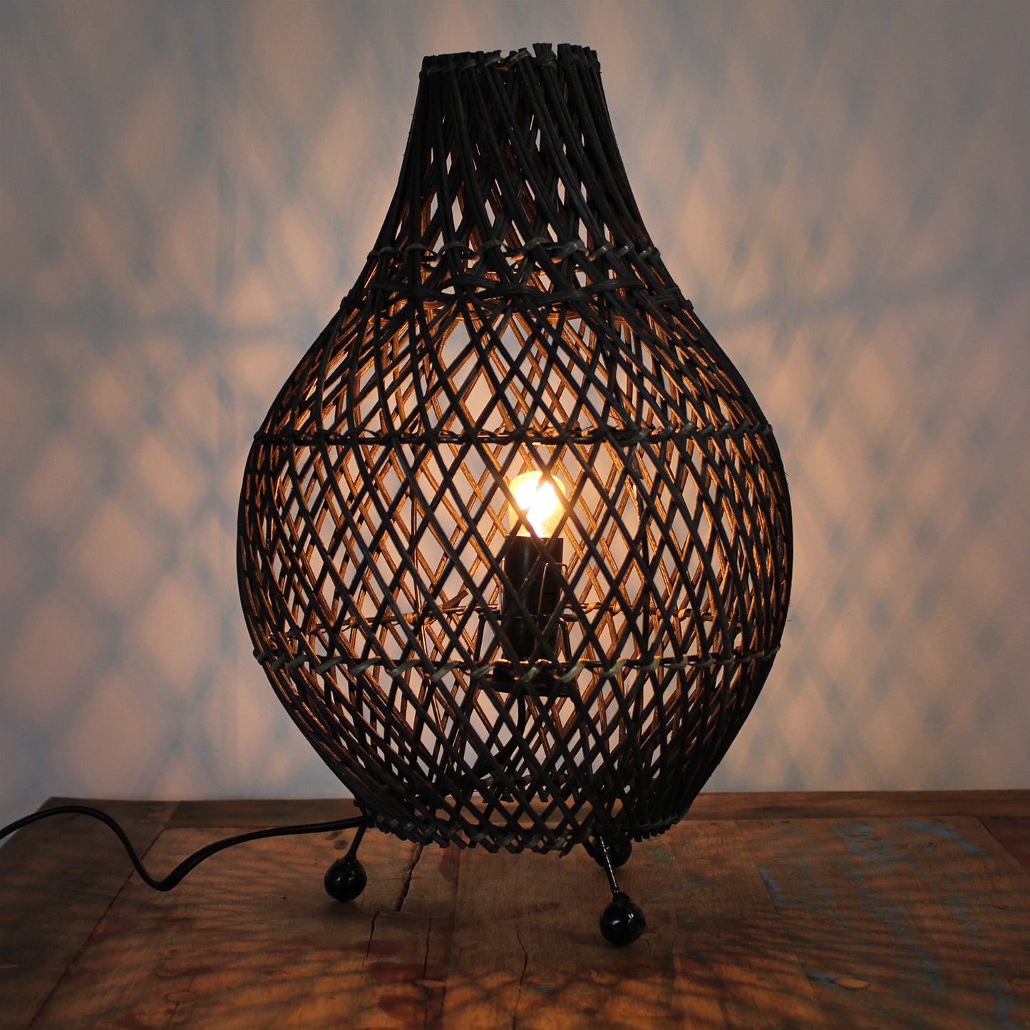 Dark brown rattan lamp glowing softly, casting warm light patterns ideal for cozy living spaces.