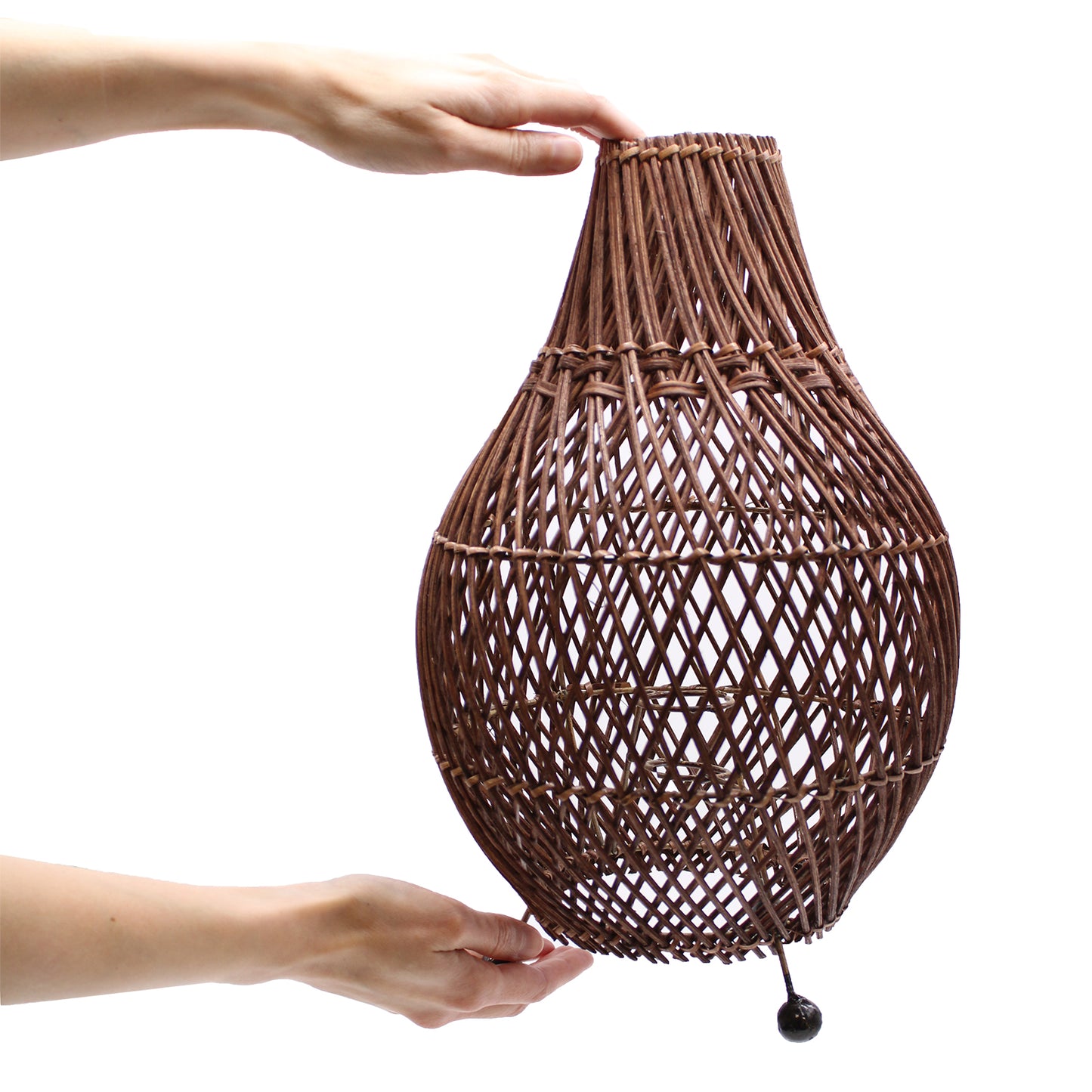 Dark brown rattan lamp being held to show scale and organic craftsmanship, suitable for earthy home decor.