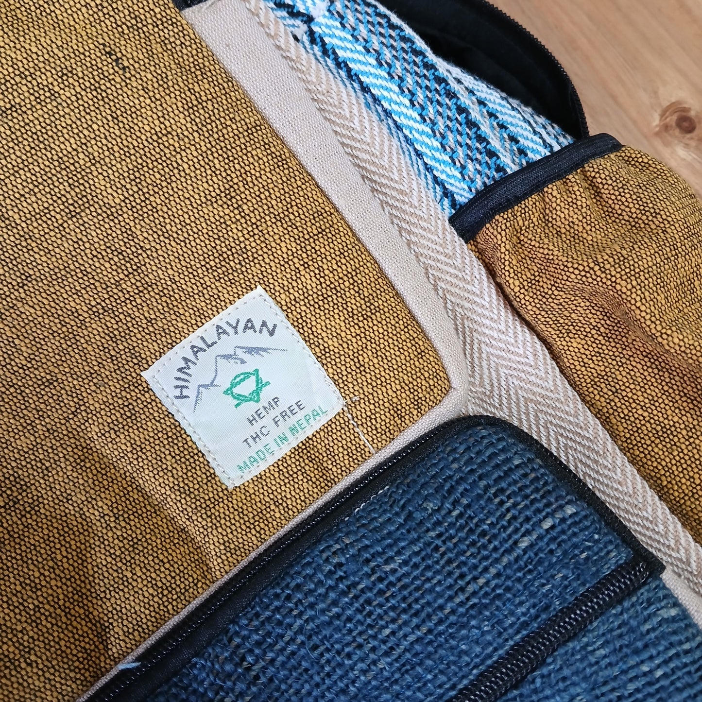 Close-up of handmade hemp backpack label showing turmeric and teal woven texture, made in Nepal with THC-free sustainable materials