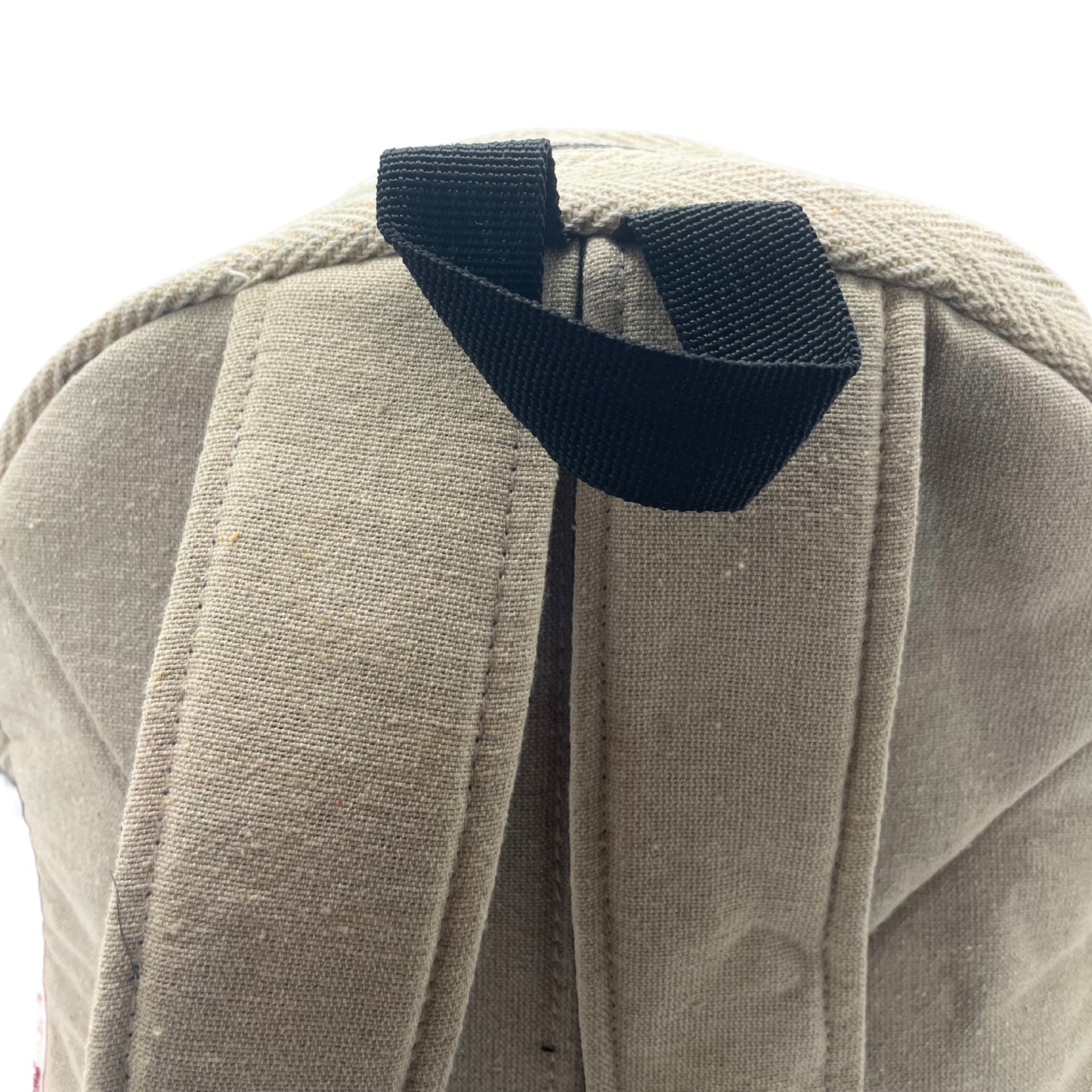 Close-up of black strap loop and reinforced stitching on hemp backpack, showing top handle for carrying ease