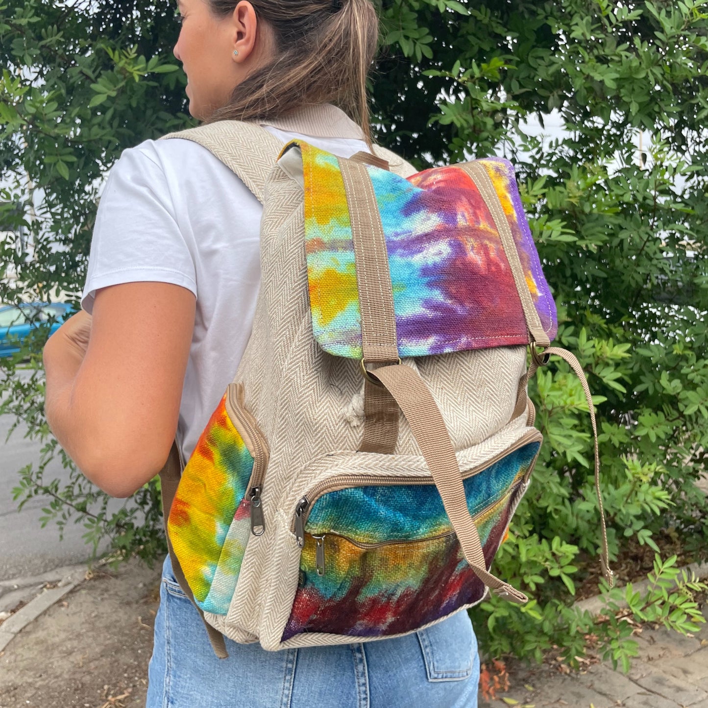 Woman wearing large square hemp backpack with rainbow tie-dye design, perfect for festivals, eco travel, and conscious everyday style