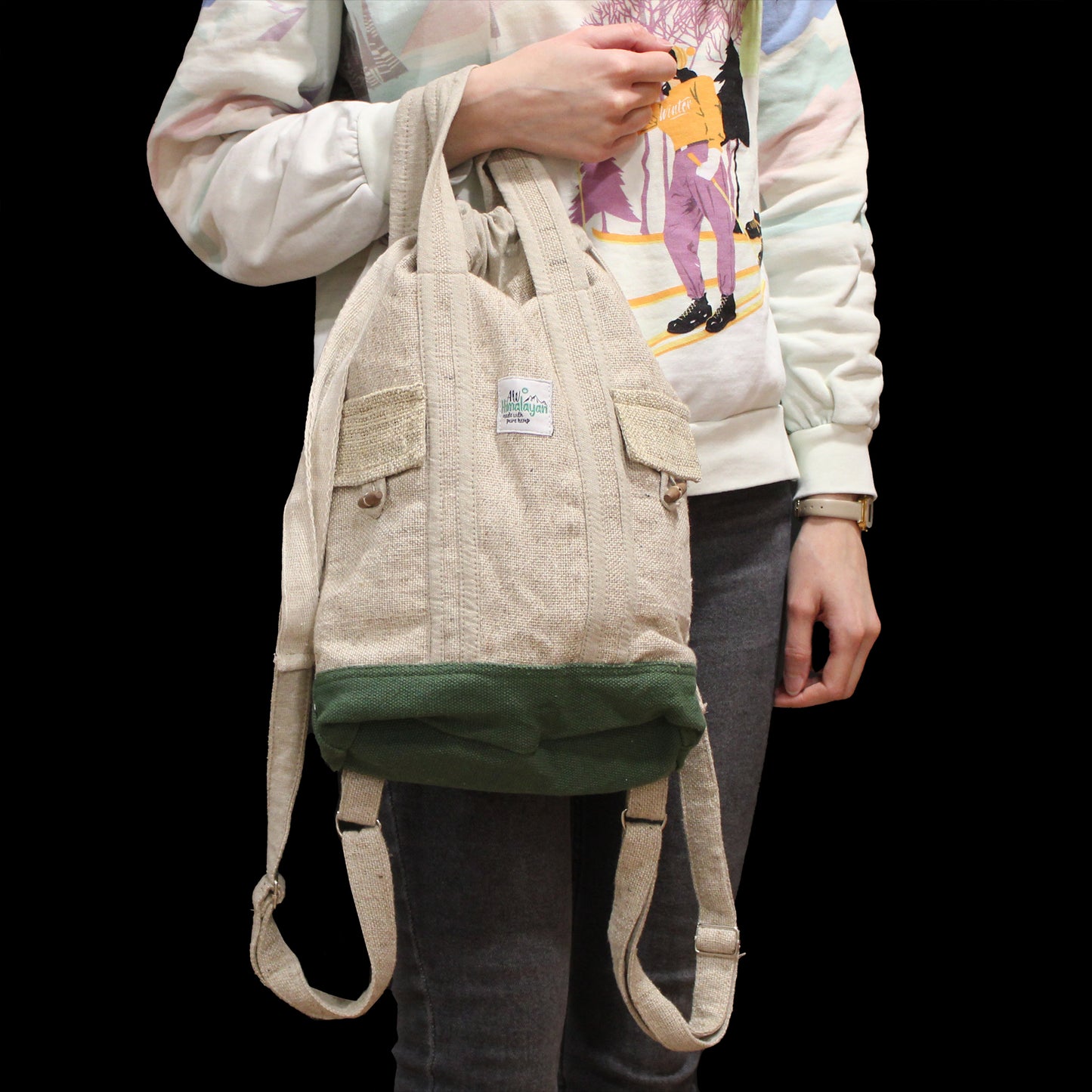 Model holding hemp and cotton eco backpack from Nepal with green base, perfect for festivals, school, or travel