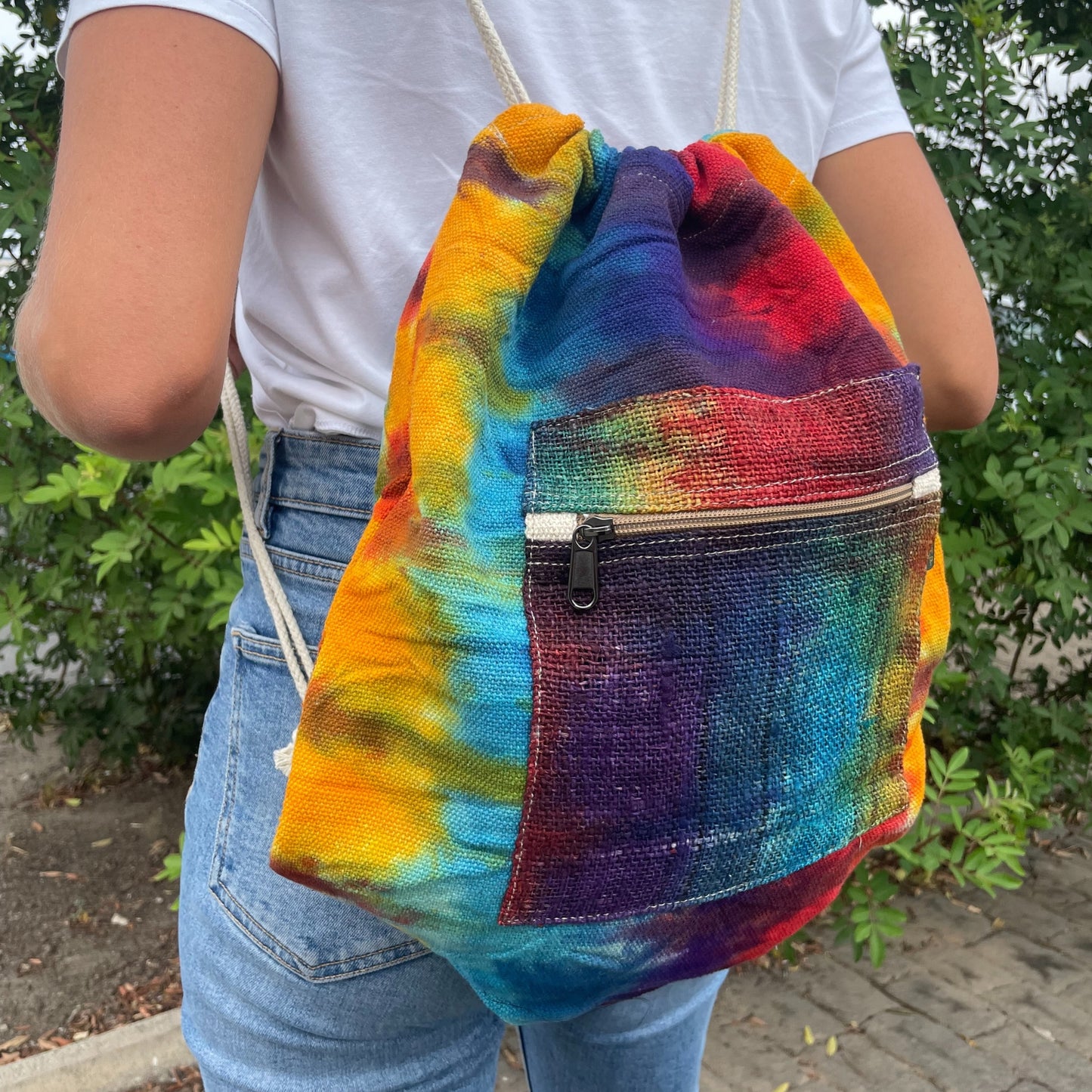Model wearing colourful tie-dye hemp drawstring bag, ideal for festivals, yoga, beach days or casual eco-conscious wear.