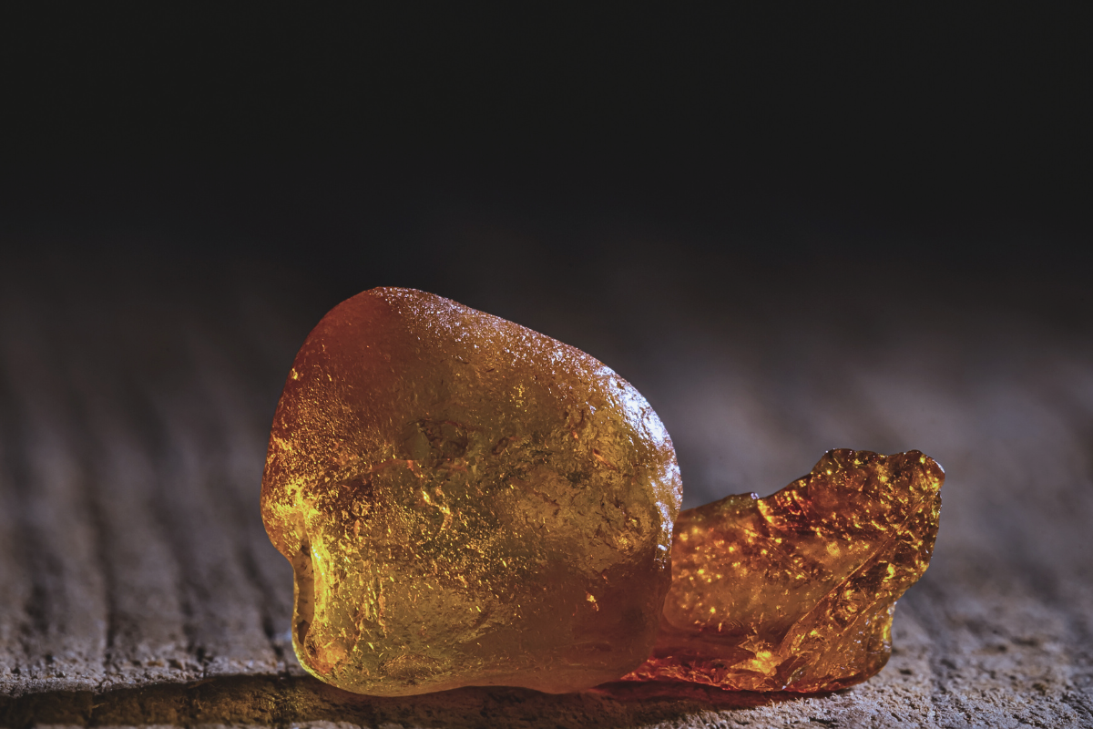 Close up of amber resin on a wooden surface, used as a reference material for Roman oil and resin cosmetic formulas in Priestess® Sapientarium