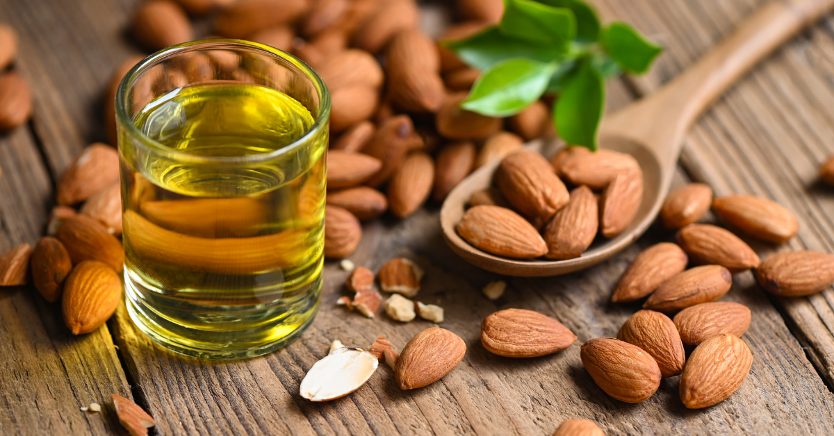 Glass of almond oil with almonds on a wooden surface