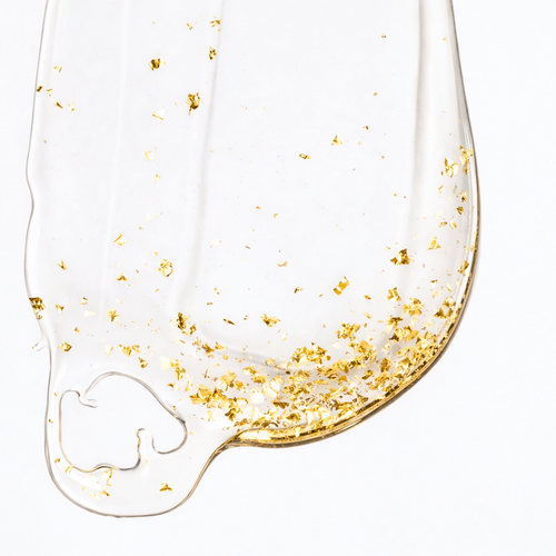 Aurum Lustrum serum with gold flakes on a beige background