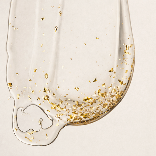 Aurum Lustrum serum with gold flakes on a beige background
