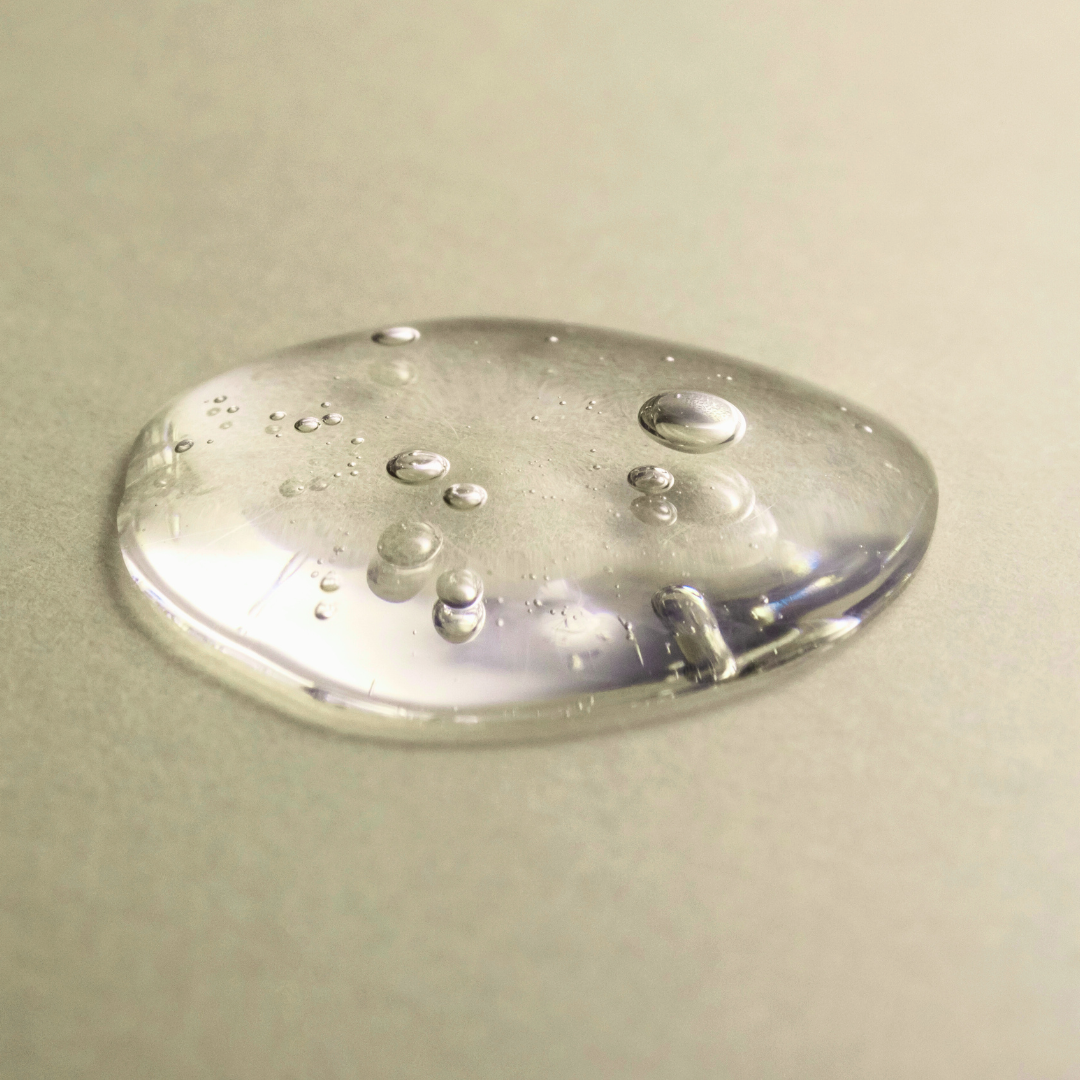 Clear liquid droplet with bubbles on a beige background