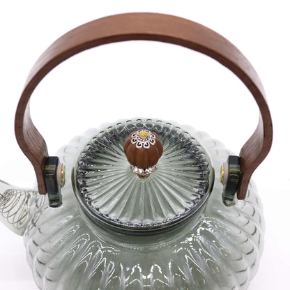 Close-up of ornate pearl-finish lid and arched wooden handle on charcoal ribbed glass teapot