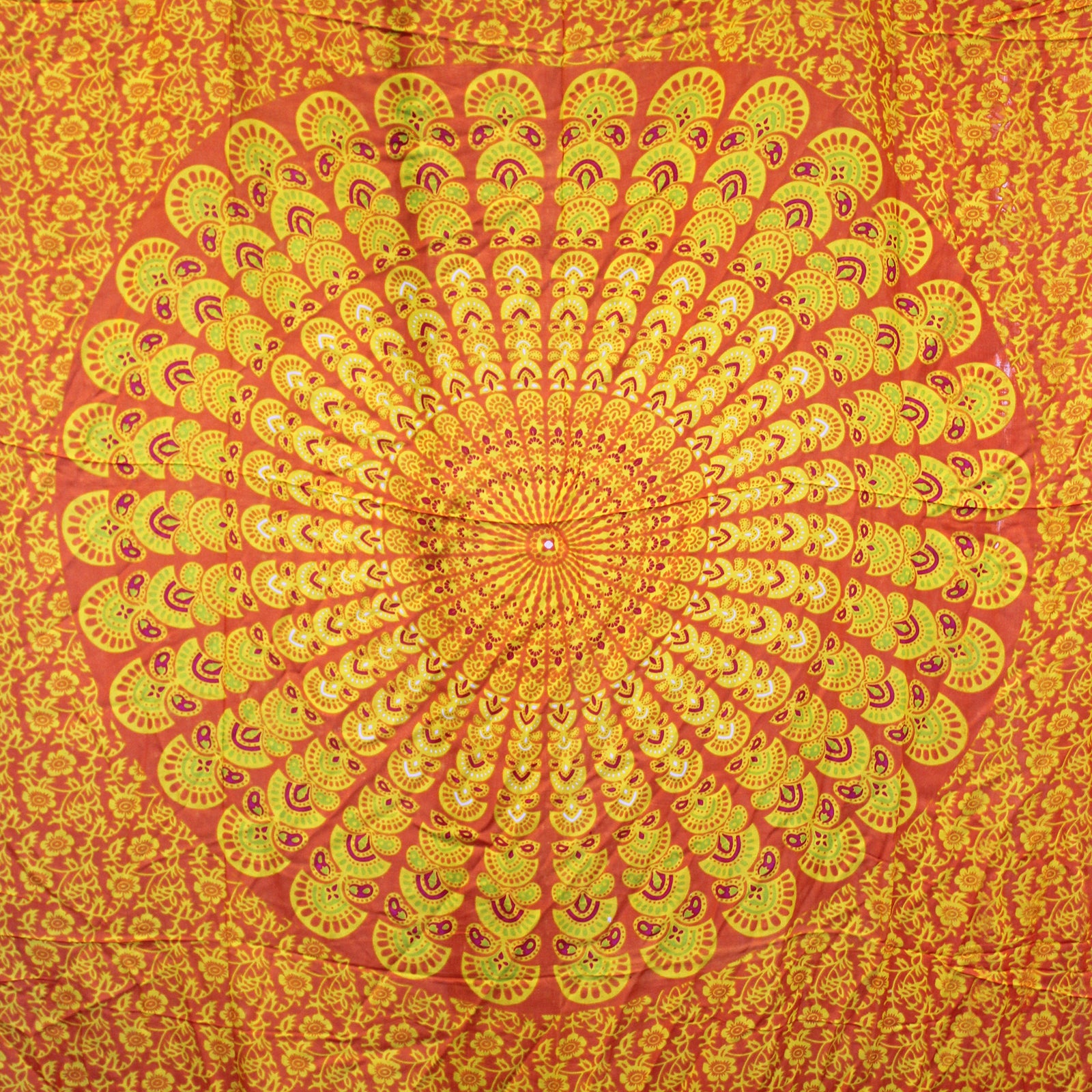 Circular mandala design in orange, yellow, and lime on full laid-out sarong with floral background
