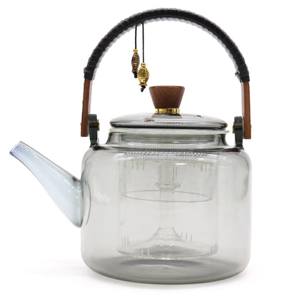 Side view of charcoal-toned glass teapot with built-in steamer and wooden knob lid