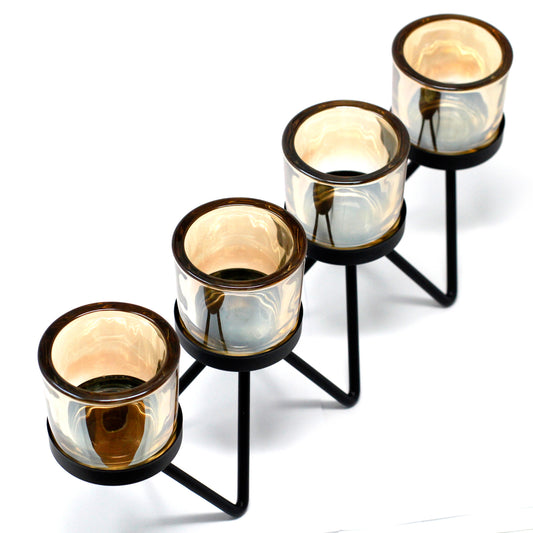 Black iron candle holder with zig-zag frame and three glass votive holders, shown against a white background for clean product presentation.