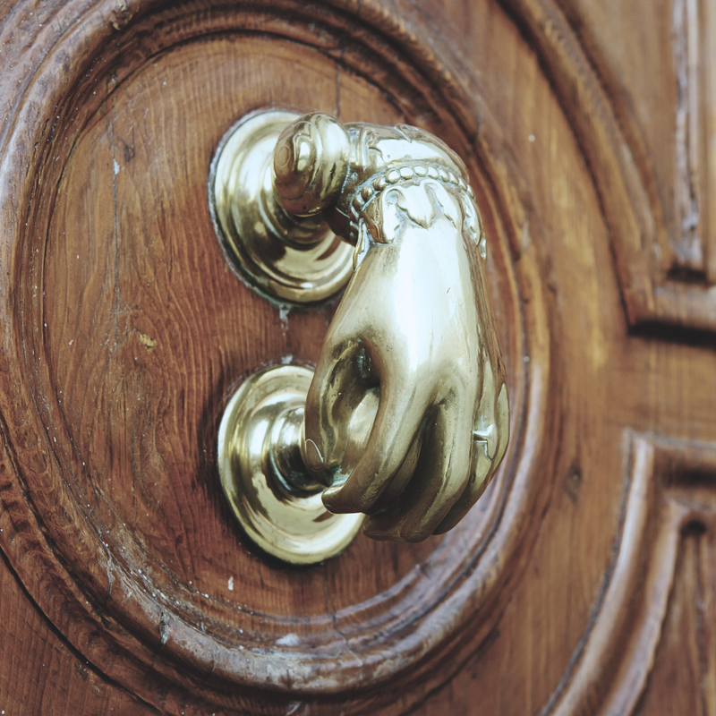 Close-up of a gold door knocker on a wooden door