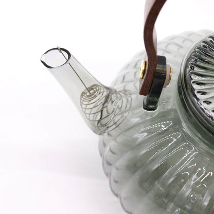 Fine detail of curved spout with charcoal-tinted glass on ribbed pearl teapot with brass-finish accents