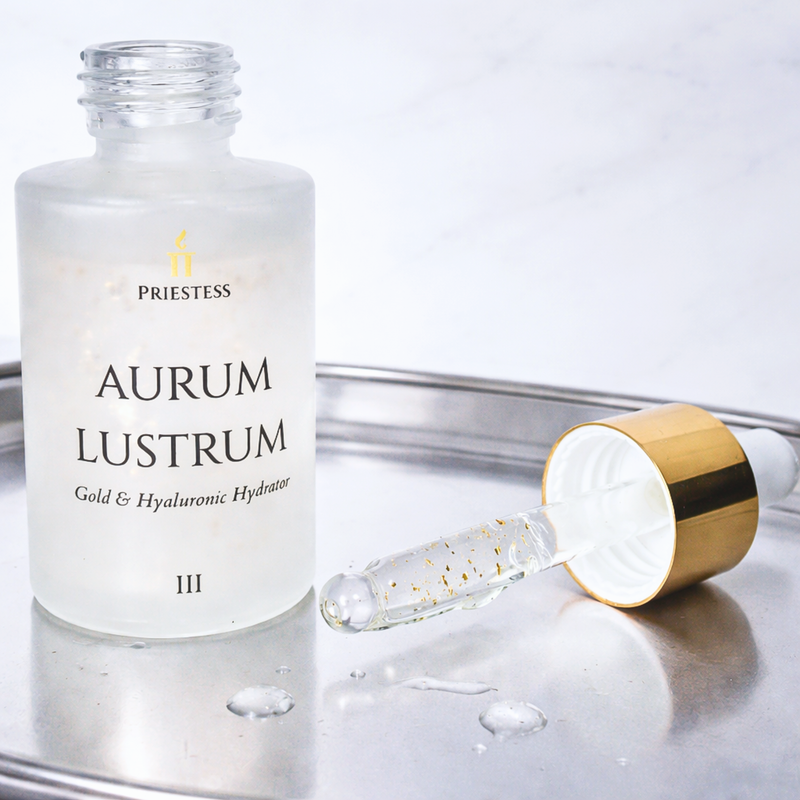 Priestess Aurum Lustrum skincare product with dropper on a reflective surface