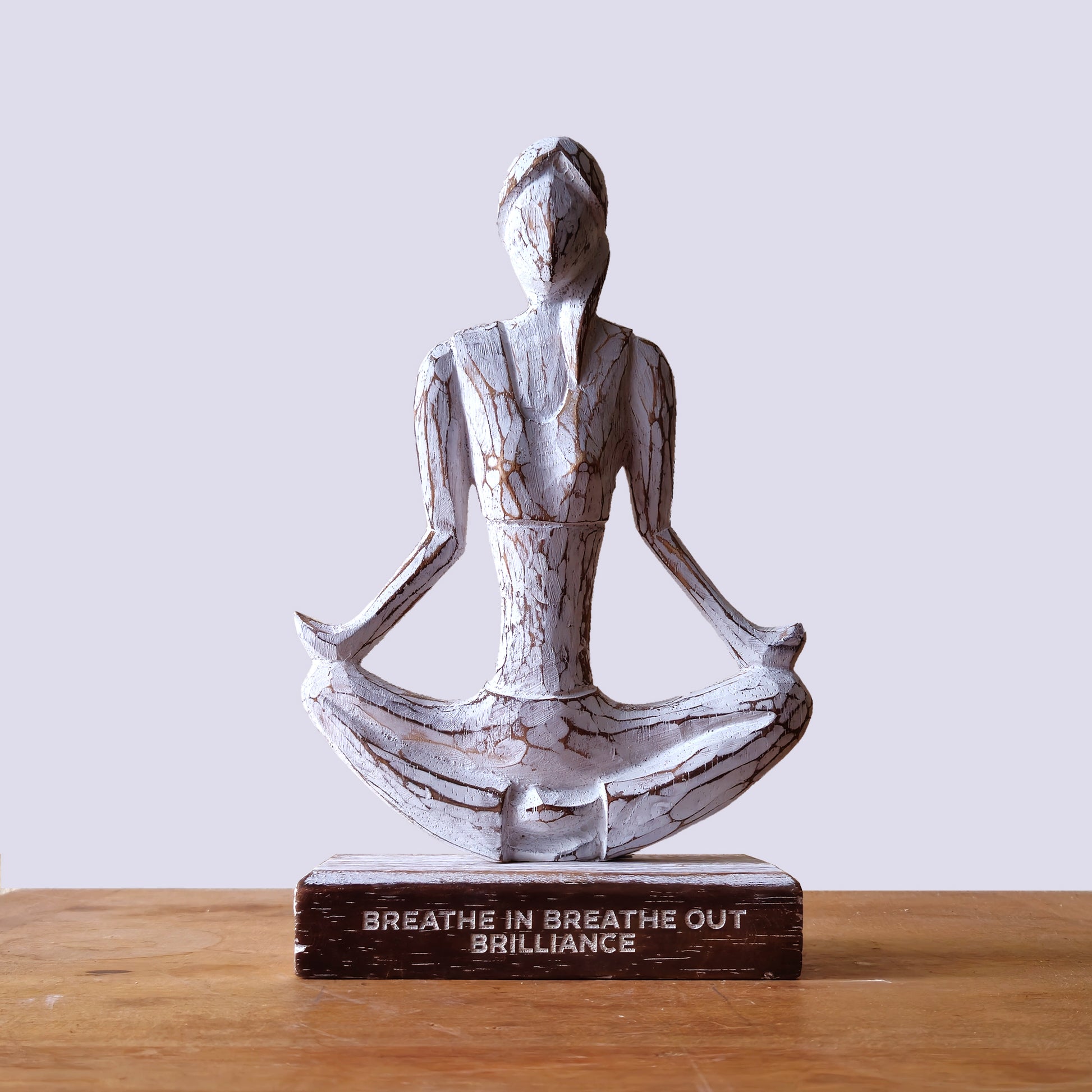 Wooden yoga lady in Easy Pose seated on a desk, styled for workspace serenity or meditation corner.