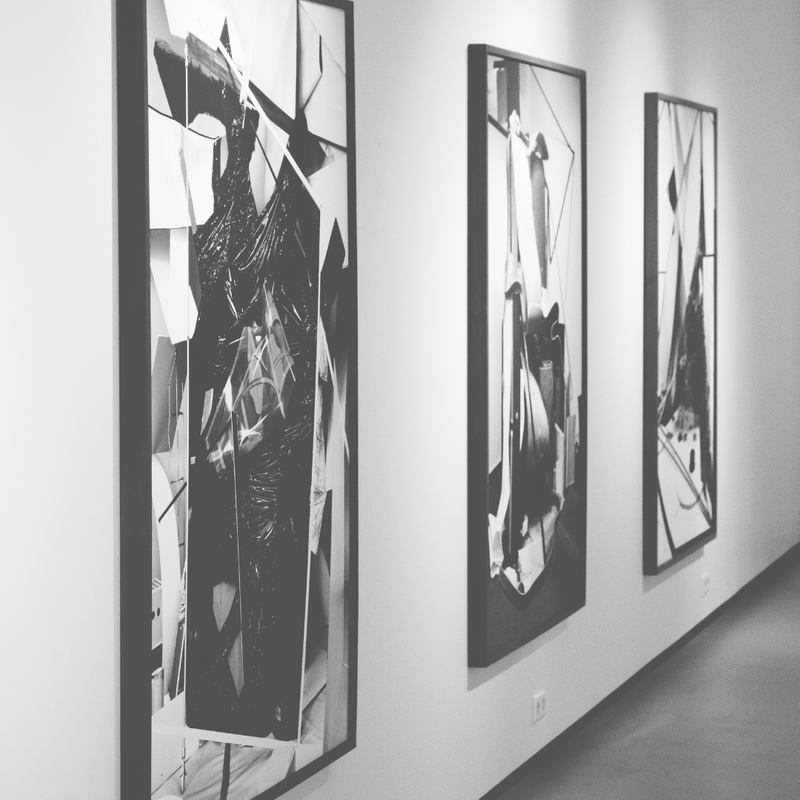 Three abstract black and white artworks on a wall in an art gallery.