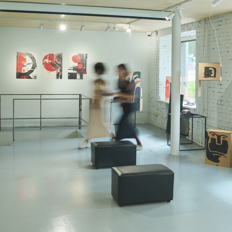 Two people walking through a modern art gallery with abstract paintings on the walls.