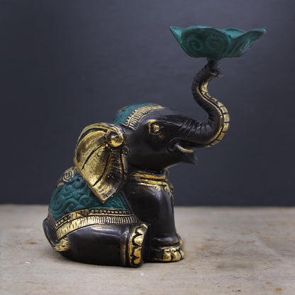 Brass elephant candle holder with green lotus dish shown on stone surface against dark grey background, spiritual decor accessory