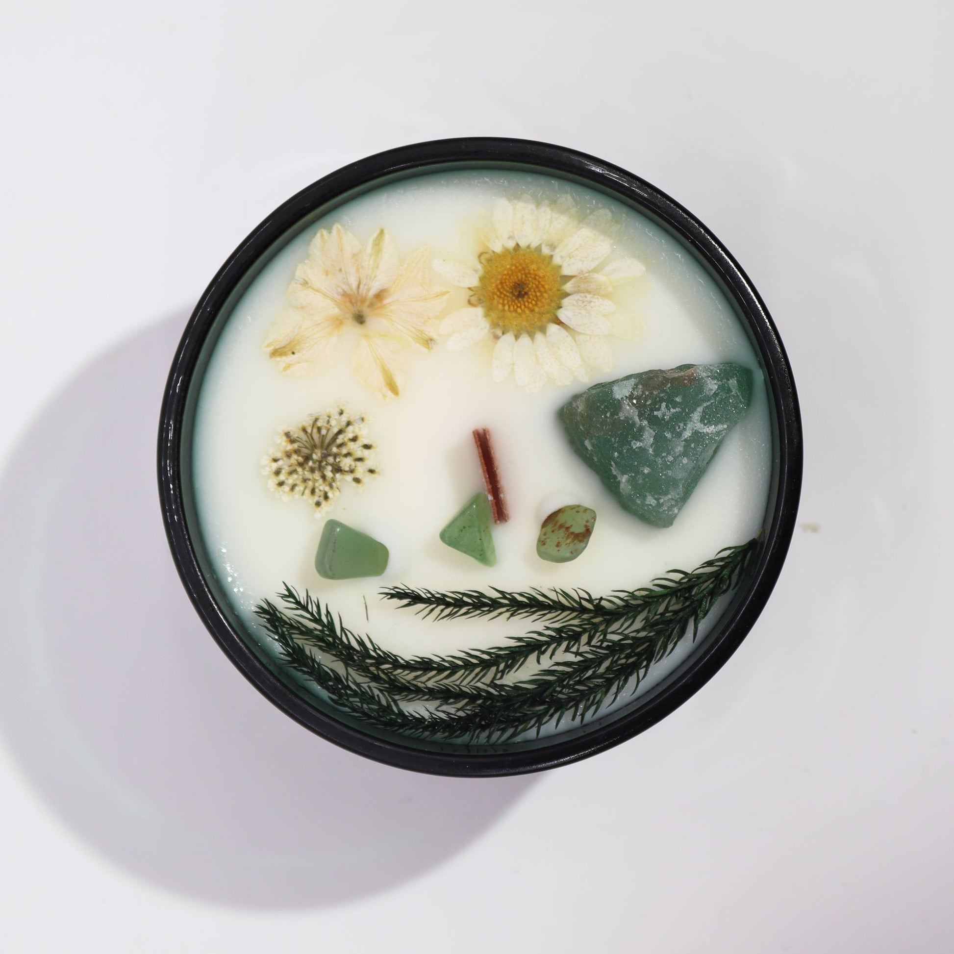 Top view of The Magician Candle showing green soy wax, embedded Jade crystals, and floral details